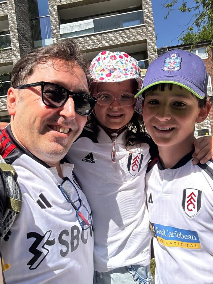 Uygar and two kids in Fulham shirts, smiling in the sun